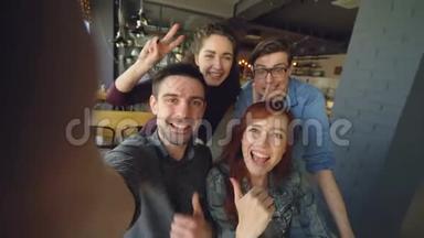 一群快乐的朋友在咖啡馆里拍了一段有趣的视频，摆<strong>姿势</strong>，微笑着<strong>拥抱</strong>和手势